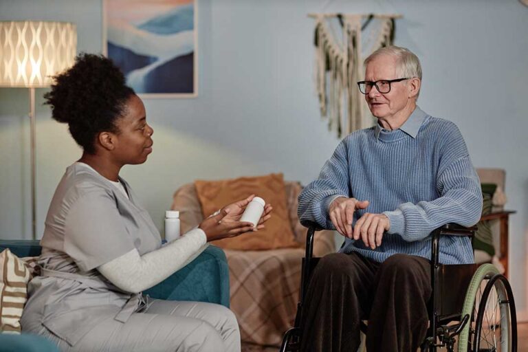 Older adult and family member sit together on a couch, sharing a heartfelt conversation surrounded by moving boxes.