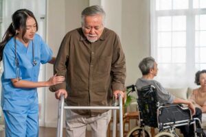 Senior woman using a walker with grab bars and non-slip mats visible in a well-lit hallway.